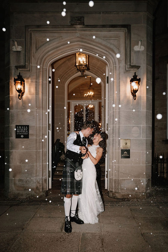 Nighttime champagne spray bride and groom outside Crossbasket Castle